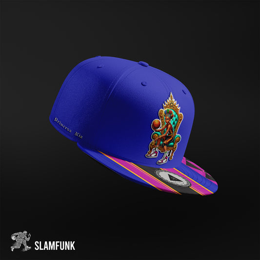 Princess Nia Snapback in royal blue, featuring an embroidered design of Princess Nia seated on a golden throne, holding a basketball. The brim showcases vibrant African-inspired patterns.